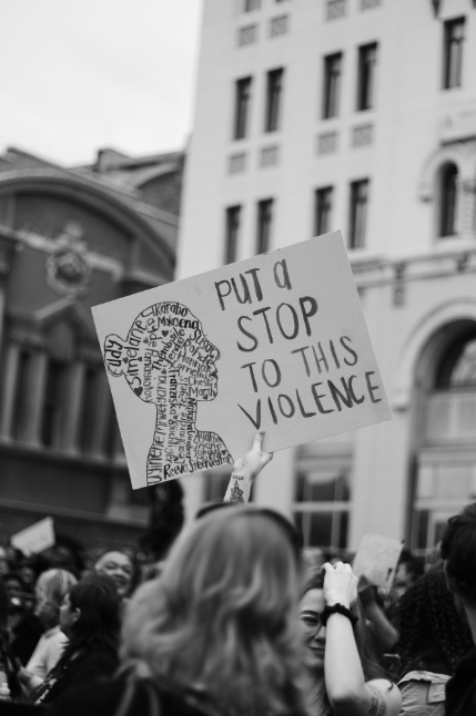 Woman holding up a sign at a protest stating "Put a stop to this violence".