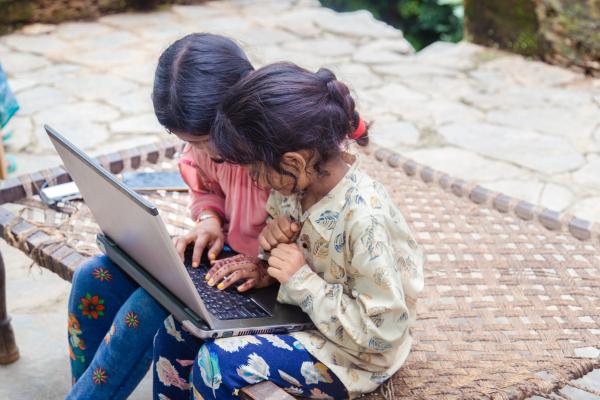 Two young girls use laptop for their school work