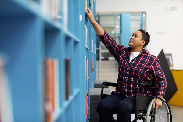 Student in wheelchair browses shelves in library