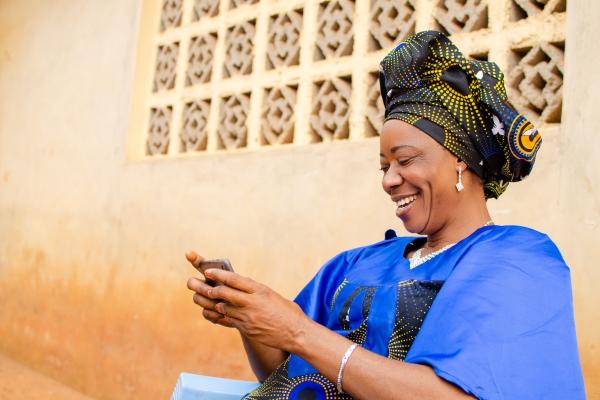 Nigerian woman smiling while using mobile phone