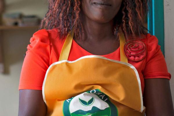 Woman standing towards camera, wearing apron and smiling.