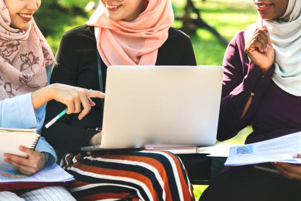 Three young Muslim women use laptop in work meeting