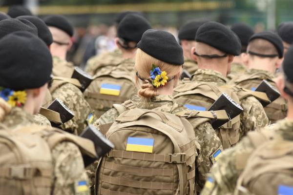 Ukrainian soldiers marching, backs to their camera, female soldier in centre