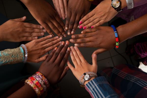 An image of women's hands palm-faced down touching fingertips in a circular position. 