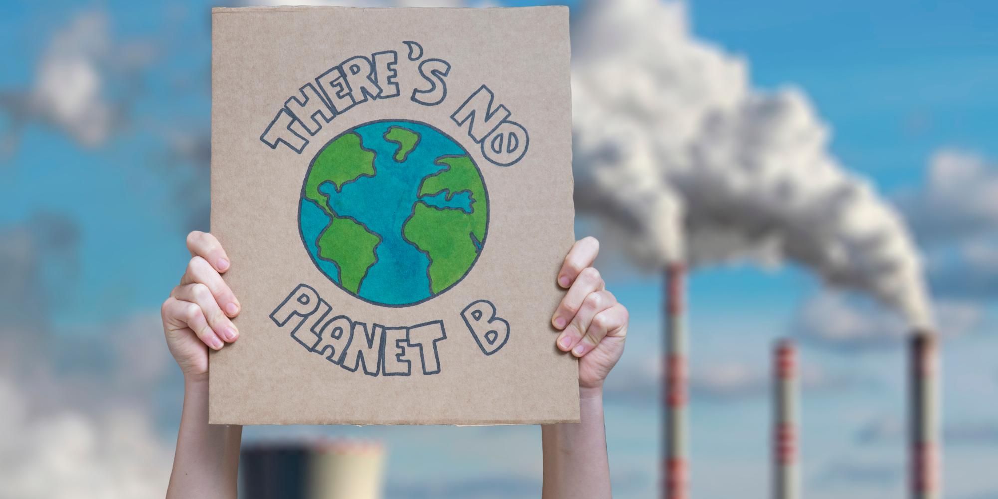 Hands hold up poster which reads 'There is no Planet B'