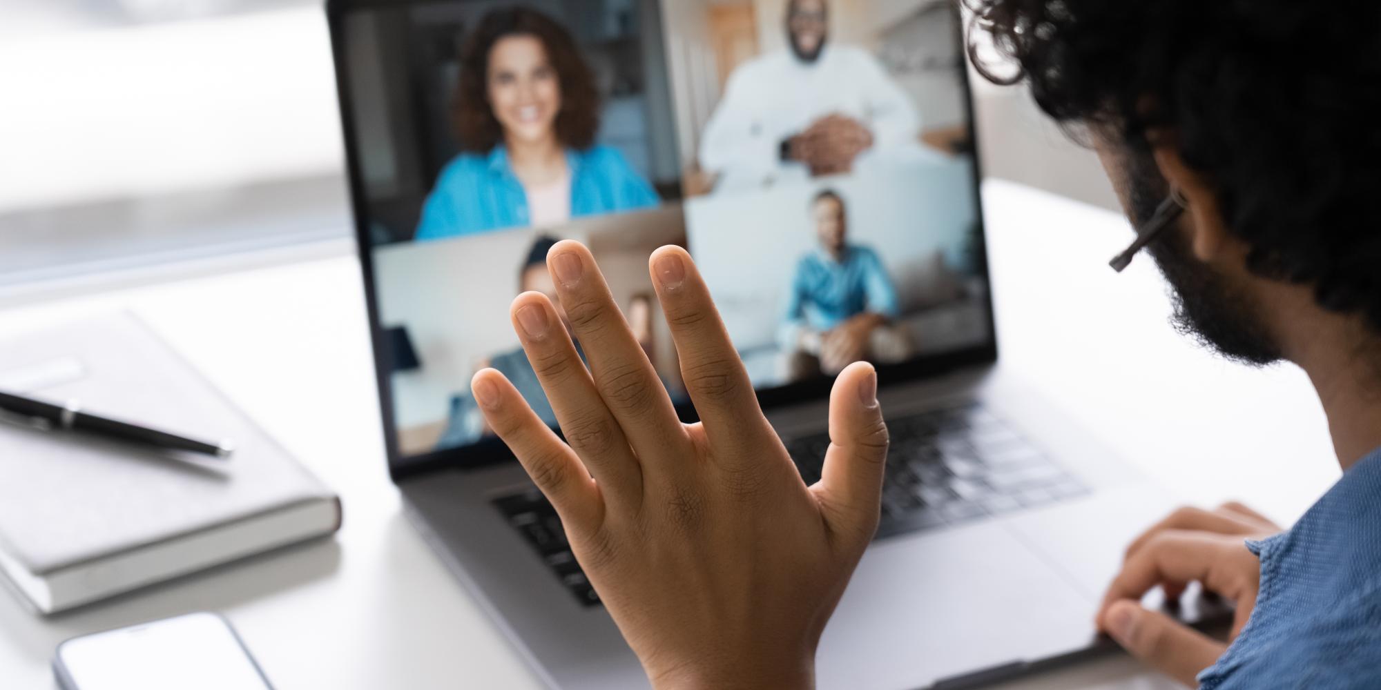 Stock photo of people working from home, waving to people on screen