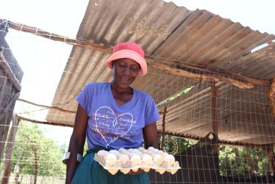 Woman carrying large crate of chicken eggs. 